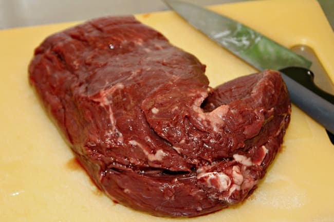 Slab of raw steak on cutting board